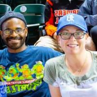 A man and woman smiling in the stands of Comerica Park